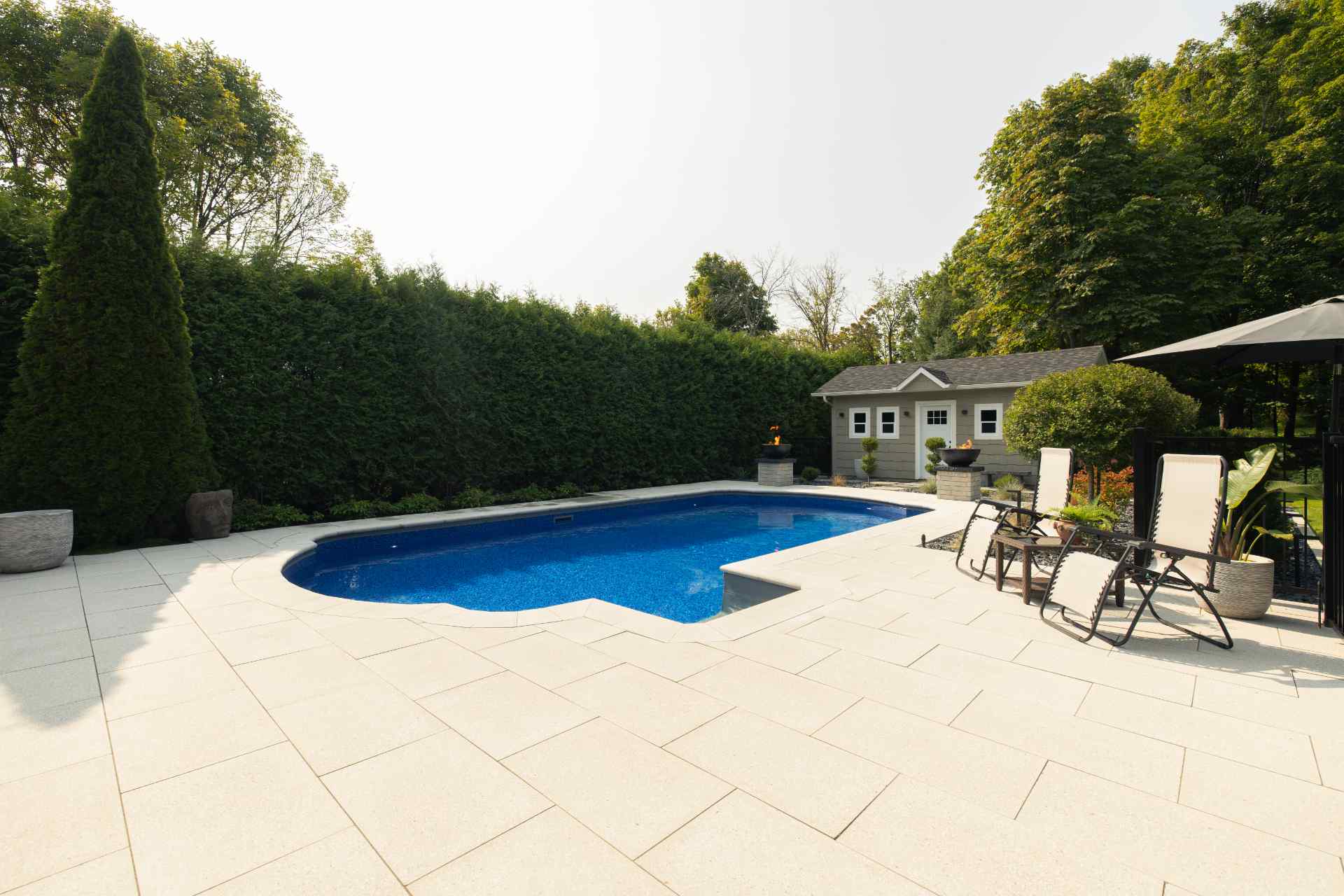 Aménagement complet autour d'une piscine creusée avec terrasse en pavé uni